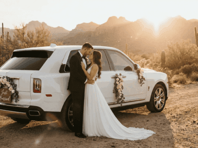 Bride and groom beside a white Rolls-Royce Cullinan in the Arizona desert at sunset